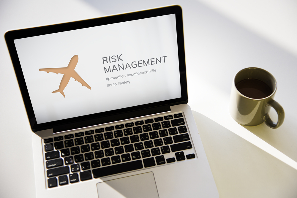 Image of laptop with airplane image and risk management sign.